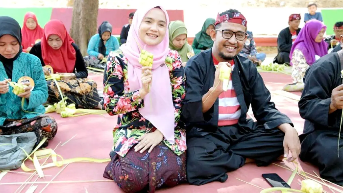 SERASI: Bupati Achmad Fauzi Wongsojudo beserta istrinya, Nia Kurnia Fauzi, saat membuat selongsong ketupat di festival ketupat yang terselenggara di tempat wisata Pantai Slopeng, Kecamatan Dasuk, Sumenep, Senin (7/4/2025). (PROKOPIM SUMENEP UNTUK JPRM)