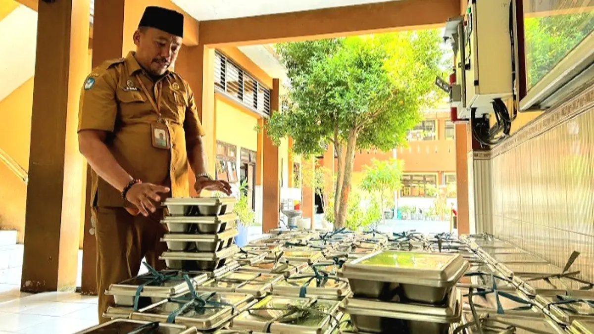 KEMBALI DIDISTRIBUSIKAN: Guru SDN Kemayoran 1 Bangkalan mengecek ompreng makanan sebelum dikembalikan kepada penyalur Senin (13/7). (VIVIN AGUSTIN HARTONO/JPRM)