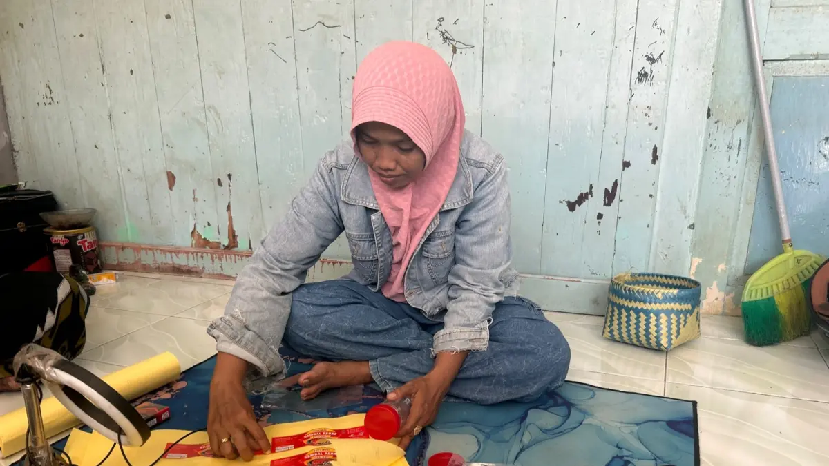 TEKUN: Toyyibah memasang label sambal pedas yang diproduksi sendiri di rumahnya, di Kelurahan Banyuanyar, Sampang, Jumat (17/7).