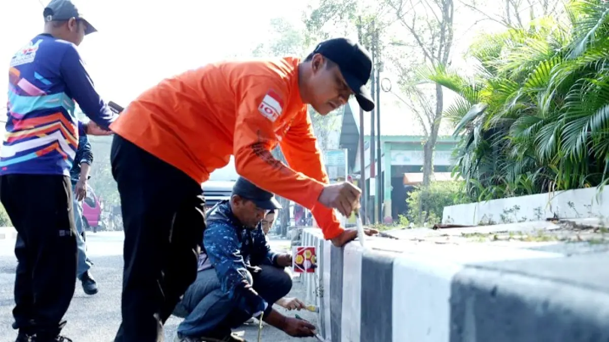 BERI CONTOH BAIK: Bupati Bangkalan Lukman Hakim mengecat trotoar di ruas Jalan Soekarno-Hatta Selasa (21/7). (PROKOPIM UNTUK JPRM)