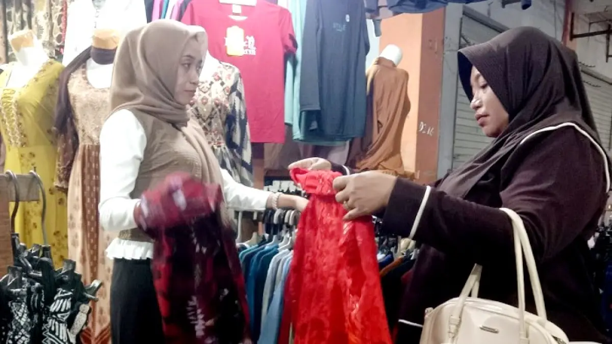 TRANSAKSI: Pedagang baju melayani pembeli di Pasar Ki Lemah Duwur Bangkalan Kamis (23/7). (INA HERDIYANA/JPRM)
