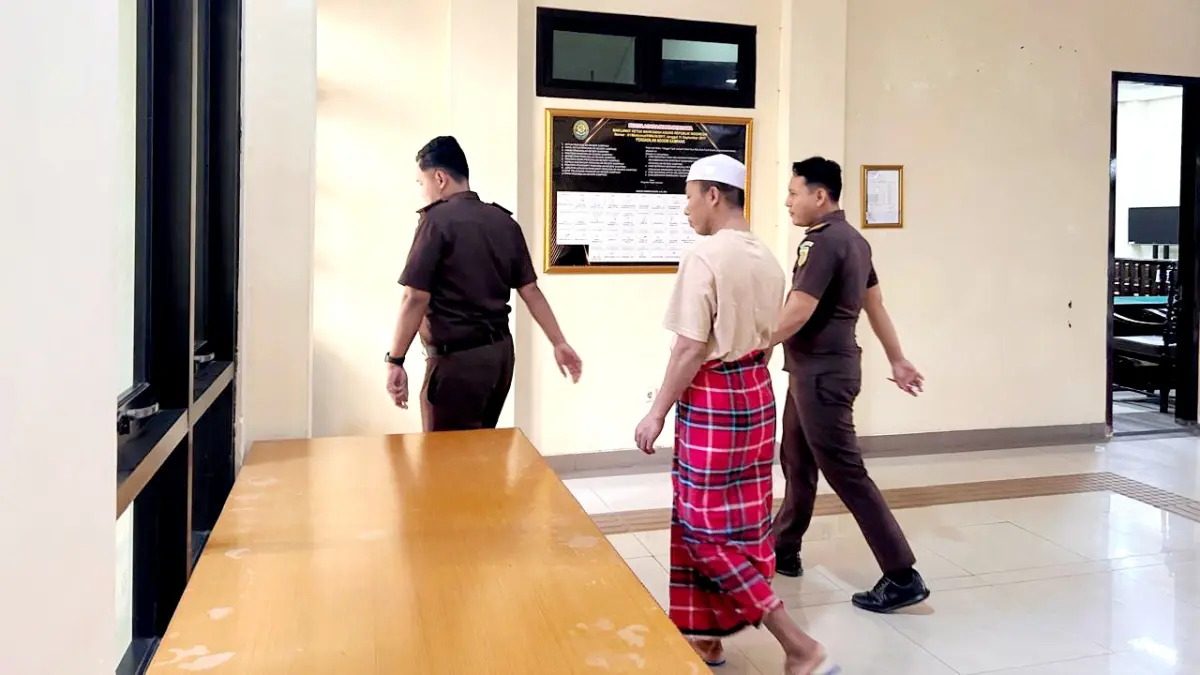 DIKAWAL KETAT: Salah satu terdakwa perkara tindak asusila anak di bawah umur dikawal petugas tahanan kejaksaan di Sampang, Rabu (22/7). (UBAIDILLAHIR RAIE/JPRM)