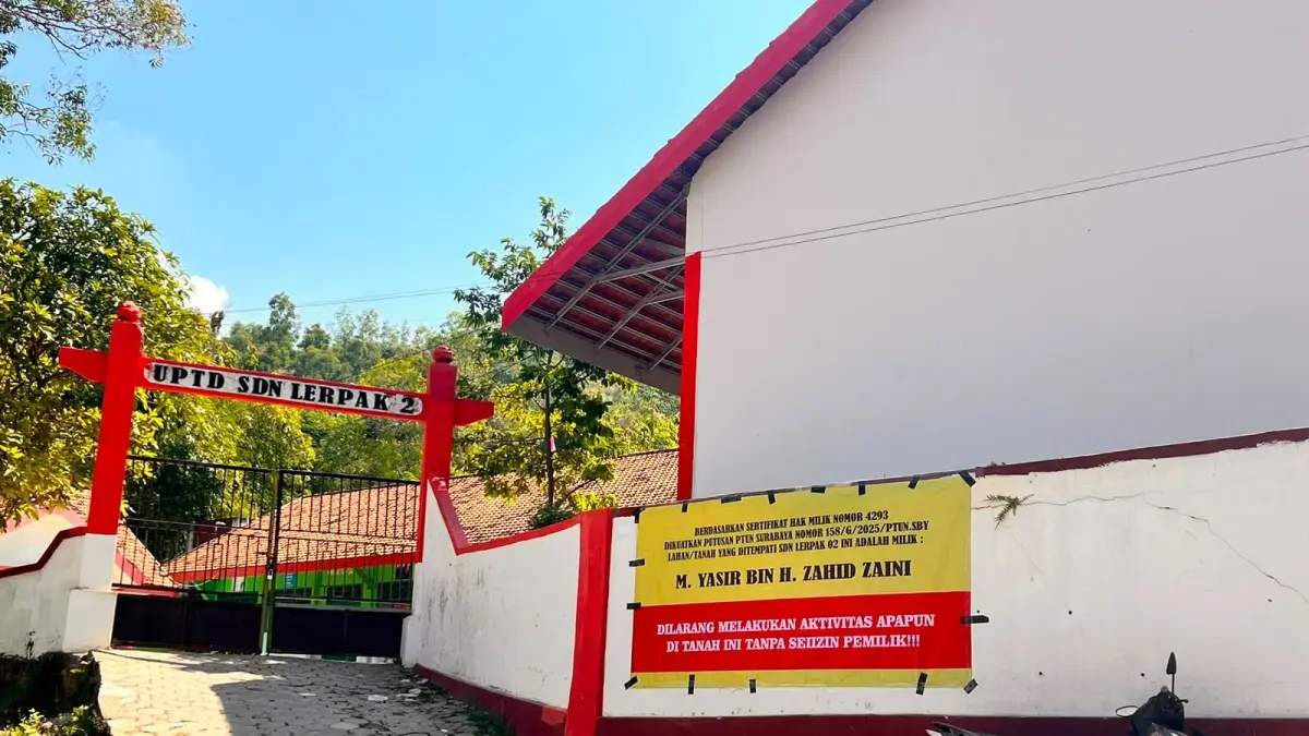 SENGKETA: Banner berisi tulisan larangan dilarang melakukan aktivitas apapun  
di tanah ini tanpa seizin pemilik tertempel di pagar SDN Lerpak 2, Kecamatan Geger, Bangkalan.