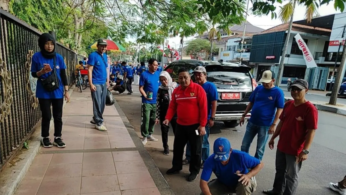 TURUN LANGSUNG: Sekkab Bangkalan Ismet Effendi (kaus merah) memimpin langsung kegiatan bersih-bersih dan mengecat trotoar di Alun-alun, Selasa (28/7).