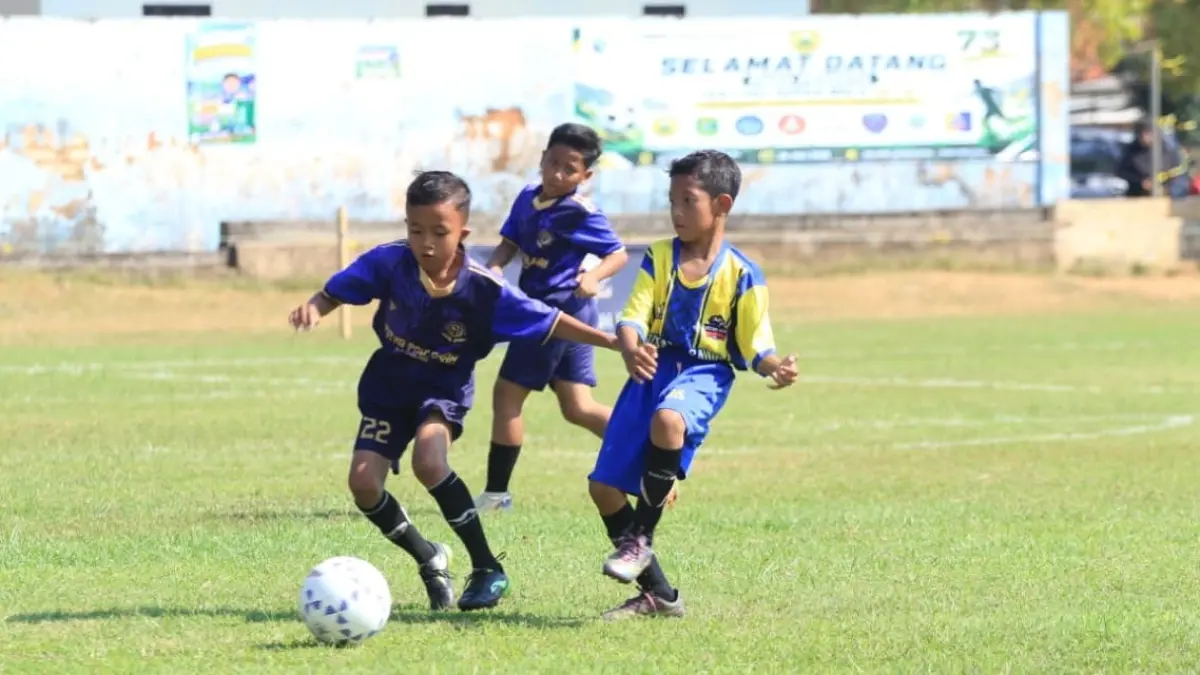 SENGIT: Pemain U-10 Klub Sepak Bola Putra Pahlawan Sampang saat mencoba melewati lawannya pada Festival Sepak Bola Anniversary Hizbul Wathan ke-73 di Lapangan Sepak Bola Sawunggaling, Pasongsongan, Minggu (26/7).