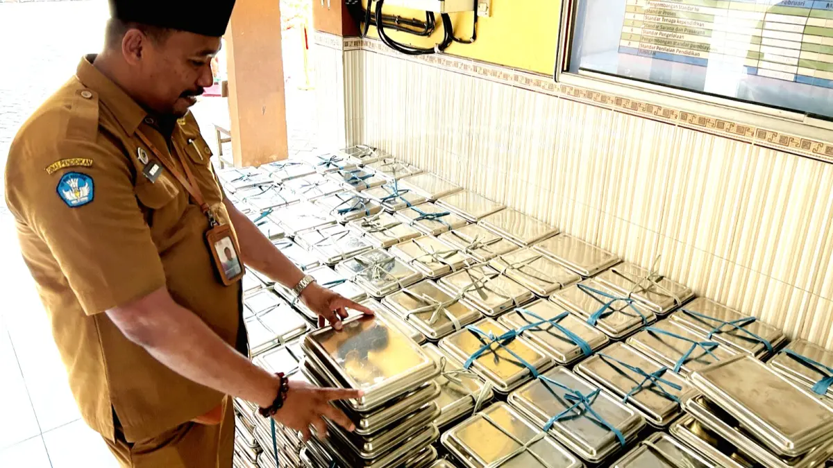 MENUMPUK: Guru SDN Kemayoran 1 Bangkalan tengah mengecek ompreng sebelum dikembalikan ke dapur, Senin (13/7). (VIVIN AGUSTIN HARTONO/JPRM)