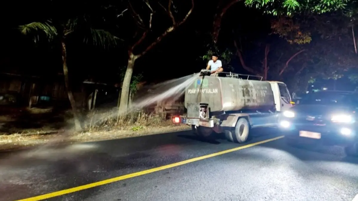 DEMI KEAMANAN: Petugas gabungan menyiram jalan yang licin di kawasan Desa Paterongan, Kecamatan Galis, Bangkalan, pada Selasa (11/8) malam. (HUMAS POLRES BANGKALAN UNTUK JPRM)