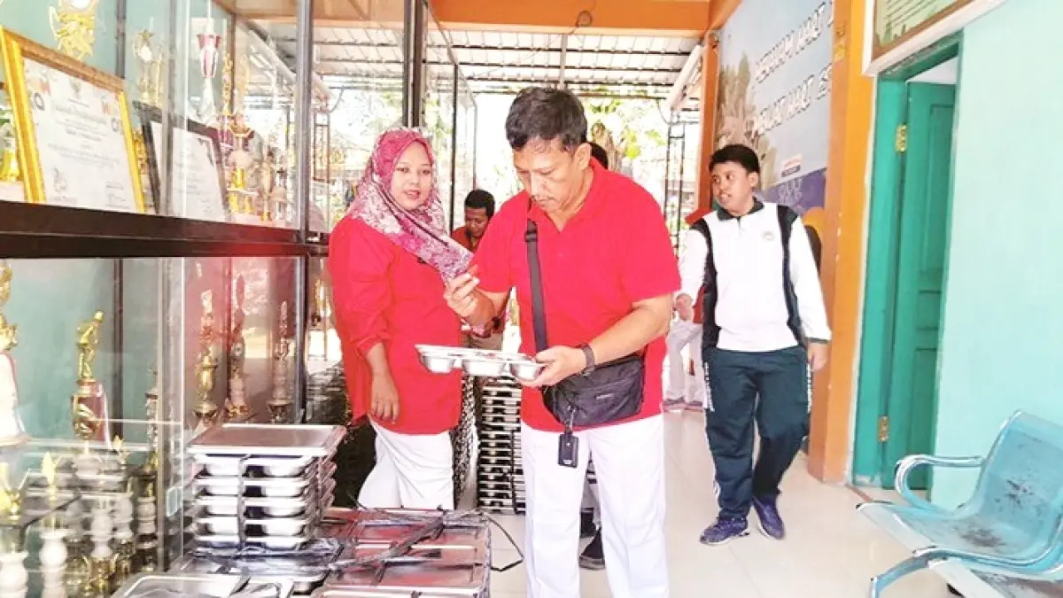 PROGRAM NASIONAL: Tenaga kependidikan SMAN 2 Pamekasan sedang mengecek menu MBG sebelum disalurkan kepada siswa, Rabu (12/8). (M. KHOLIL RAMLI/JPRM)