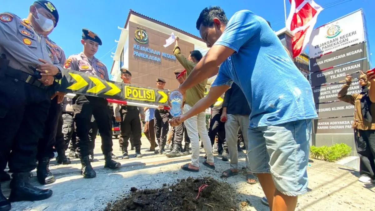 BAU MENYENGAT: Aktivis tabur kotoran sapi di sela-sela aksi unjuk rasa di kantor Kejari Pamekasan, Kamis (13/8). (MOH. IQBAL AFGANI/JPRM)