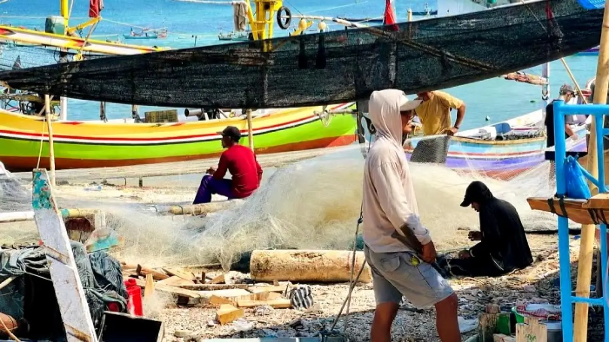 ISTIRAHAT: Nelayan sedang memperbaiki perahunya di Pulau Mandangin beberapa waktu lalu. (ABDUL WARIS UNTUK JPRM)