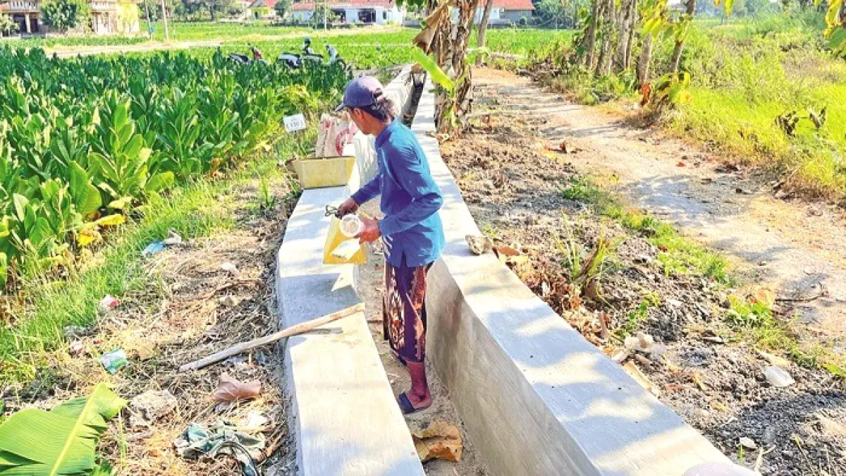 BARU SELESAI DIKERJAKAN: Pekerja sedang memperbaiki bangunan irigasi yang retak di Desa Pangongsean, Torjun, Sampang, Jumat (14/8). (DWI ARIO UNTUK JPRM)