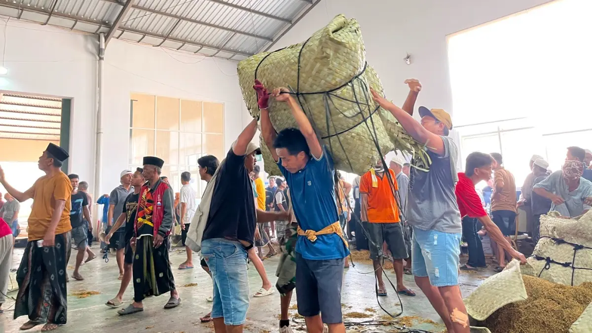 KERAHKAN TENAGA: Pekerja memanggul tembakau di Gudang PT Bawang Mas Grup, Pamekasan, Minggu (16/8).