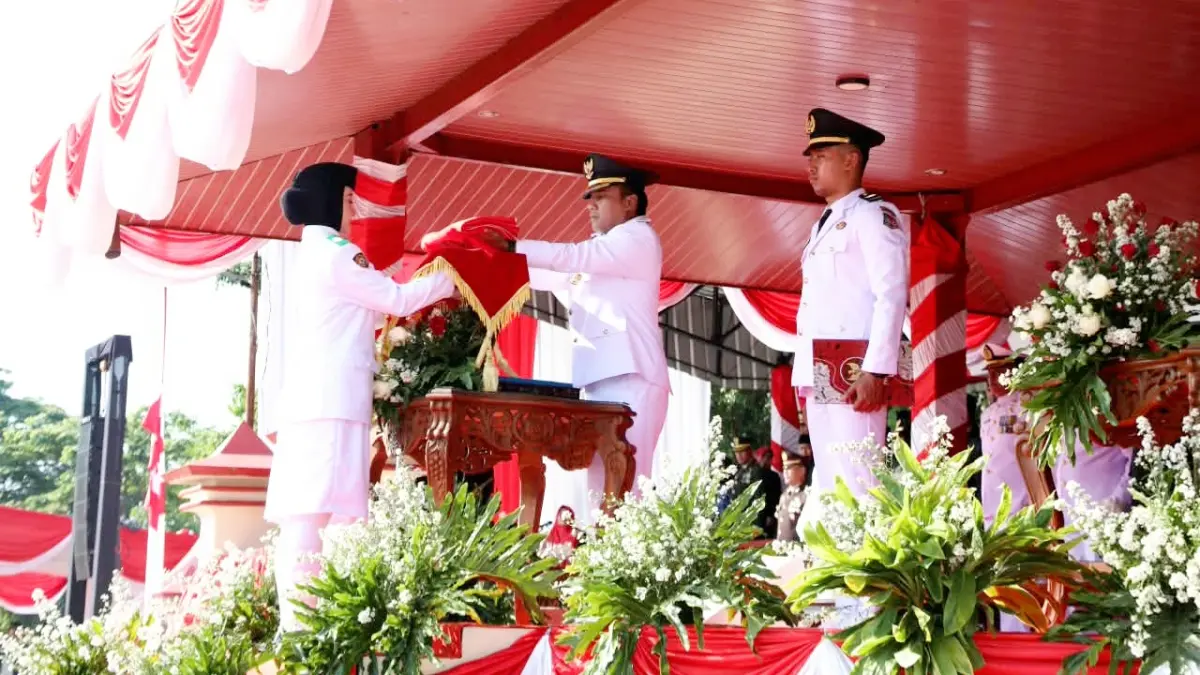 KHIDMAT: Bupati Bangkalan Lukman Hakim menyerahkan bendera Merah Putih kepada Paskibraka Upacara HUT Ke-81 Kemerdekaan RI di alun-alun Senin (17/8). (PROKOPIM UNTUK JPRM)
