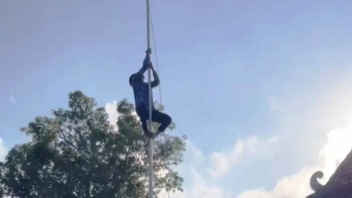 TANPA PENGAMAN: Moh. Syaifullah, ASN PPPK paro waktu Kecamatan Pamekasan memanjat tiang bendera pada upacara peringatan HUT Ke-81 Kemerdekaan RI, Senin (17/8).