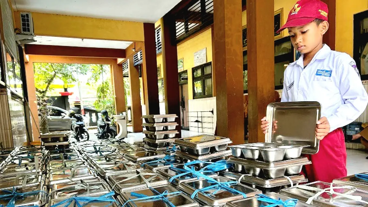 HATI-HATI: Siswa SDN Kemayoran 1 Bangkalan tengah mengecek ompreng sebelum dikembalikan ke SPPG penyalur, Senin (13/7). (VIVIN AGUSTIN HARTONO/JPRM)
