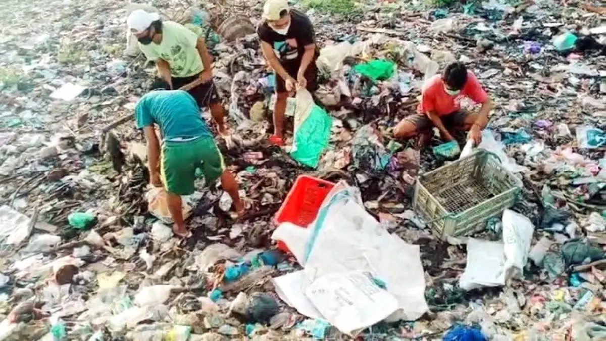 BERSERAKAN: Warga tengah memungut barang bekas di sekitar sampah yang berserakan di Desa Pulau Mandangin, Kecamatan Kota Sampang, Sabtu (22/8). (ADI UNTUK JPRM)