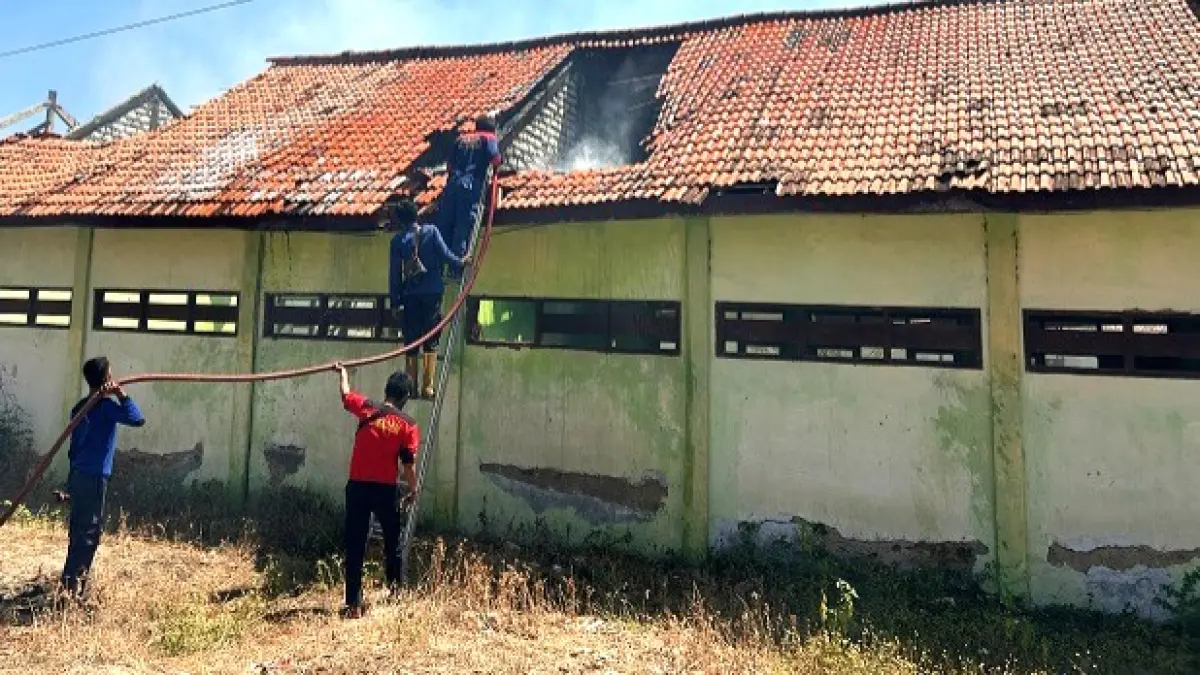 DIPADAMKAN: Petugas pemadam kebakaran memadamkan atap SDN Rongtengah 5 Sampang yang dilalap si jago merah Selasa (25/8). (UBAIDILLAHIR RA’IE/JPRM)