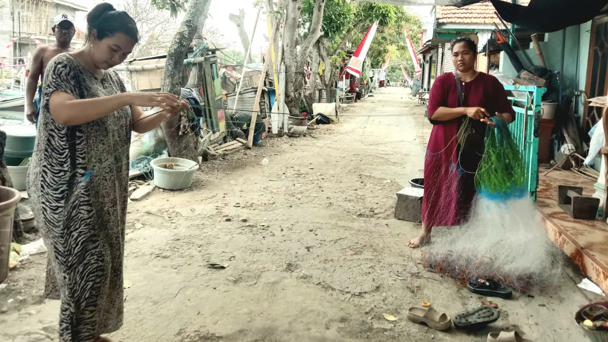 DIPERBAIKI: Istri nelayan memperbaiki jaring sebelum dibawa melaut oleh nelayan di Kampung Bandaran, Kelurahan Pejagan, Bangkalan, Rabu (26/8). (INA HERDIYANA/JPRM)