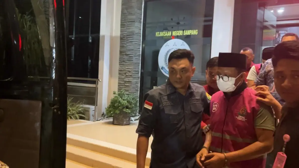 DITAHAN: Mantan Kadispendik Sampang MF digiring petugas Kejari Sampang usai ditetapkan tersangka, Kamis (27/8) malam. 