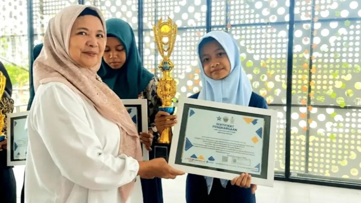 TALENTA MUDA: Calista Vida Ramadhani menerima hadiah juara 1 menulis resensi tingkat SMP dari Kabid Pelayanan Perpustakaan Dispusip Bangkalan Anik Susanti, Rabu (26/8). (CALISTA VIDA RAMADHANI UNTUK JPRM)
