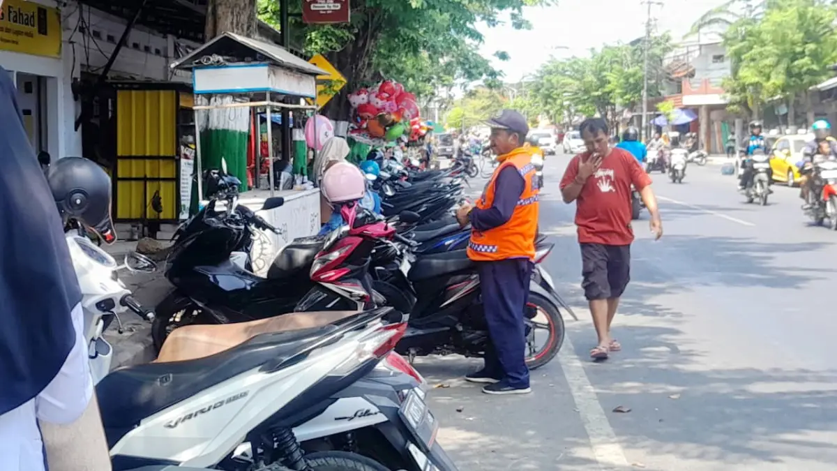 SUMBER PAD: Seorang juru parkir sedang mengatur kendaraan di Jalan Diponegoro, Kecamatan Pamekasan, Selasa (8/9).