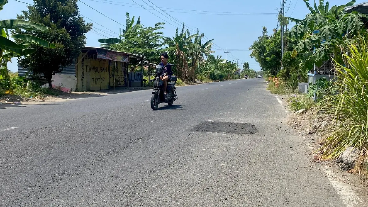 HATI-HATI: Pesepeda menghindari bekas galian di Jalan Raya Pademawu, Kamis (10/9).