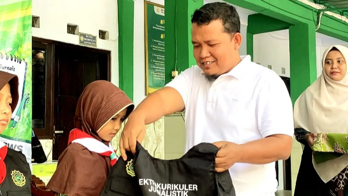 SIMBOLIS: Pemred JPRM Moh. Subhan memasangkan rompi kepada peserta Ekstrakurikuler Jurnalistik SDIT Nurul Rahmah Kemayoran, Bangkalan, Jumat (11/9). (SDIT NURUL RAHMAH UNTUK JPRM)