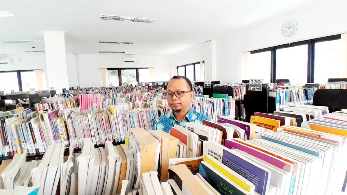 JENDELA DUNIA: Pustakawan Dispusip Pamekasan Kusairi sedang memeriksa koleksi buku yang tersimpan di rak Perpusda M. Tabrani. (M. KHOLIL RAMLI/JPRM)