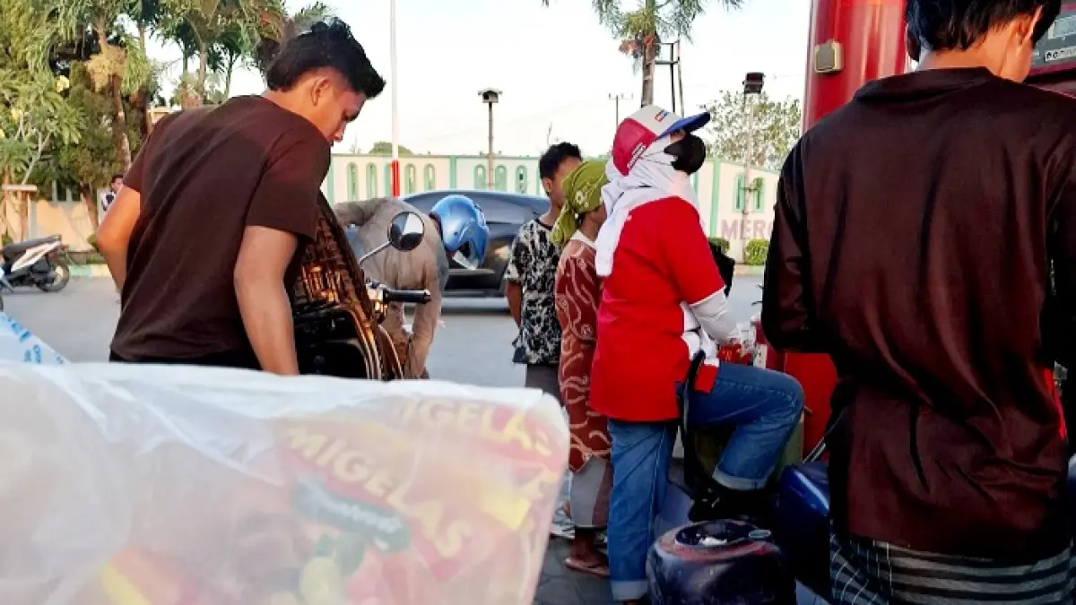 ANTRE: Petugas mengisi BBM jenis Pertalite ke jeriken warga di SPBU Lembung, Kecamatan Sepulu, Bangkalan, Minggu (13/9). (BAGUS S DHARMAWAN UNTUK JPRM)