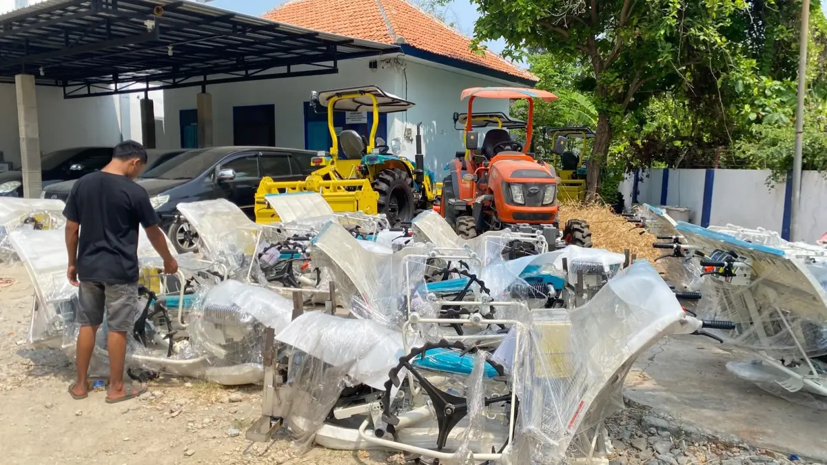 BELUM DISALURKAN: Seorang pria berada di sekitar alsintan yang bersumber dari APBN  di halaman Disperta KP Sampang, Rabu (8/9). (AYU LATIFAH/JPRM)