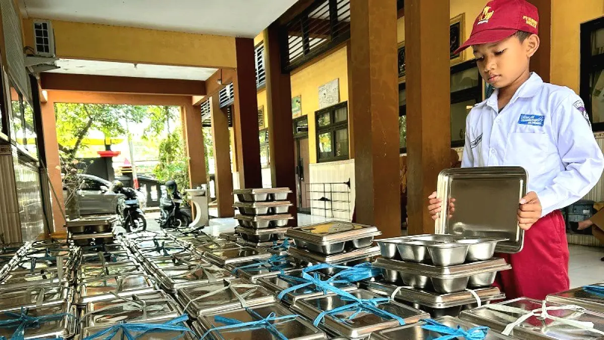 BERGIZI: Siswa SDN Kemayoran 1 Bangkalan tengah mengecek ompreng makanan sebelum dikembalikan, Senin (13/7). (VIVIN AGUSTIN HARTONO/JPRM)