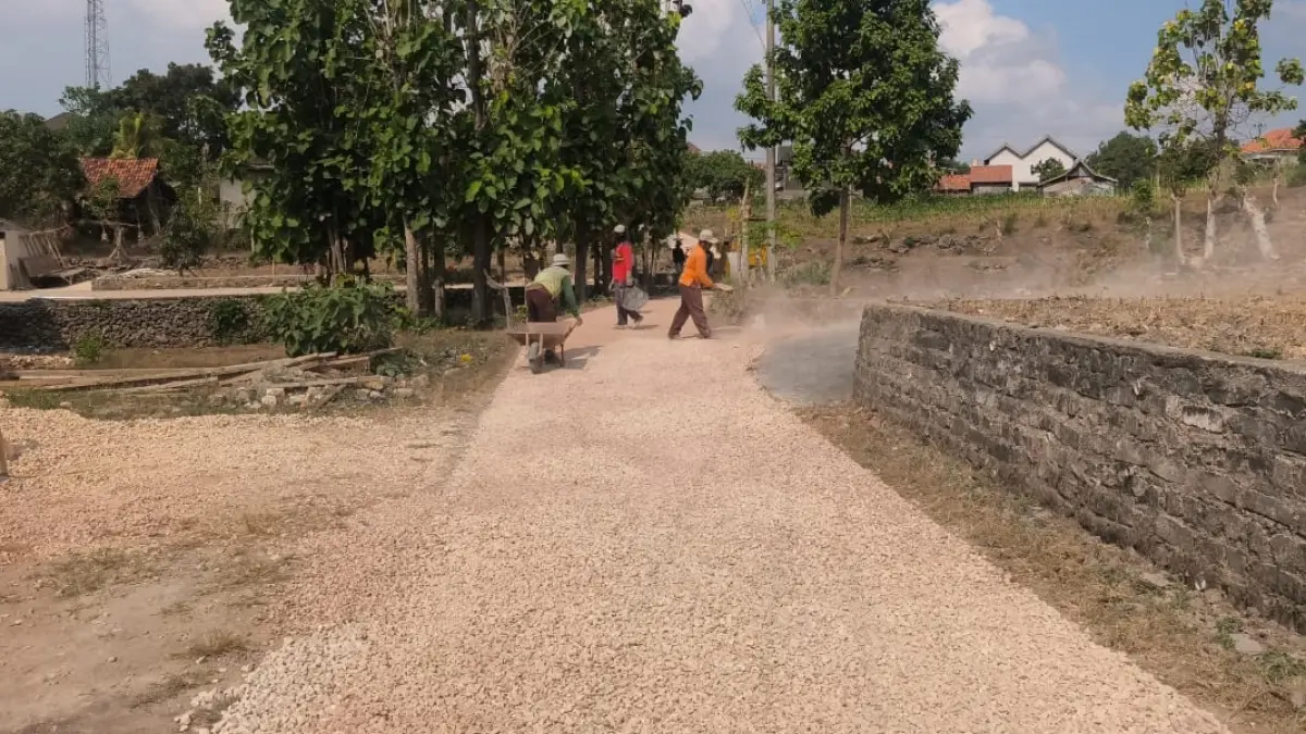 SEMANGAT: Pekerja sedang melakukan pengaspalan jalan di Dusun Pangtangis Daya, Desa Sokobanah, Kecamatan Sokobanah, Sampang. (PEMDES SOKOBANAH TENGAH UNTUK JPRM)