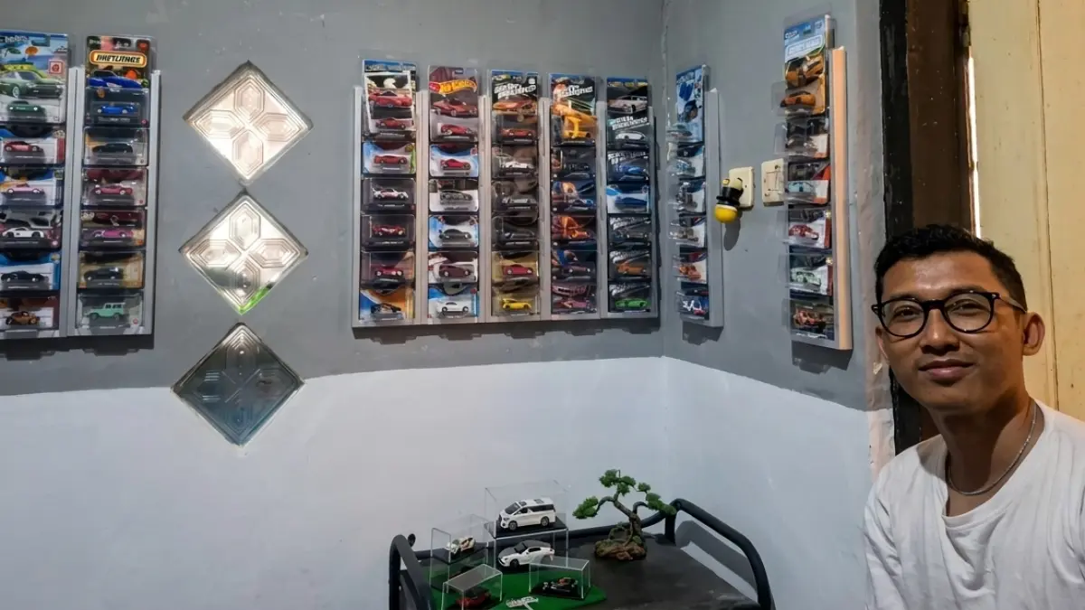 KOLEKTOR: Bagus S. Dharmawan berfoto dengan puluhan koleksi Hot Wheels yang dipajang di dinding kamarnya, Jumat (18/9).