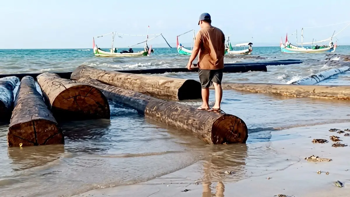 BERJEJER: Warga berada di atas kayu yang terdampar di pesisir perairan Kecamatan Dungkek, Sumenep. (ISTIMEWA)