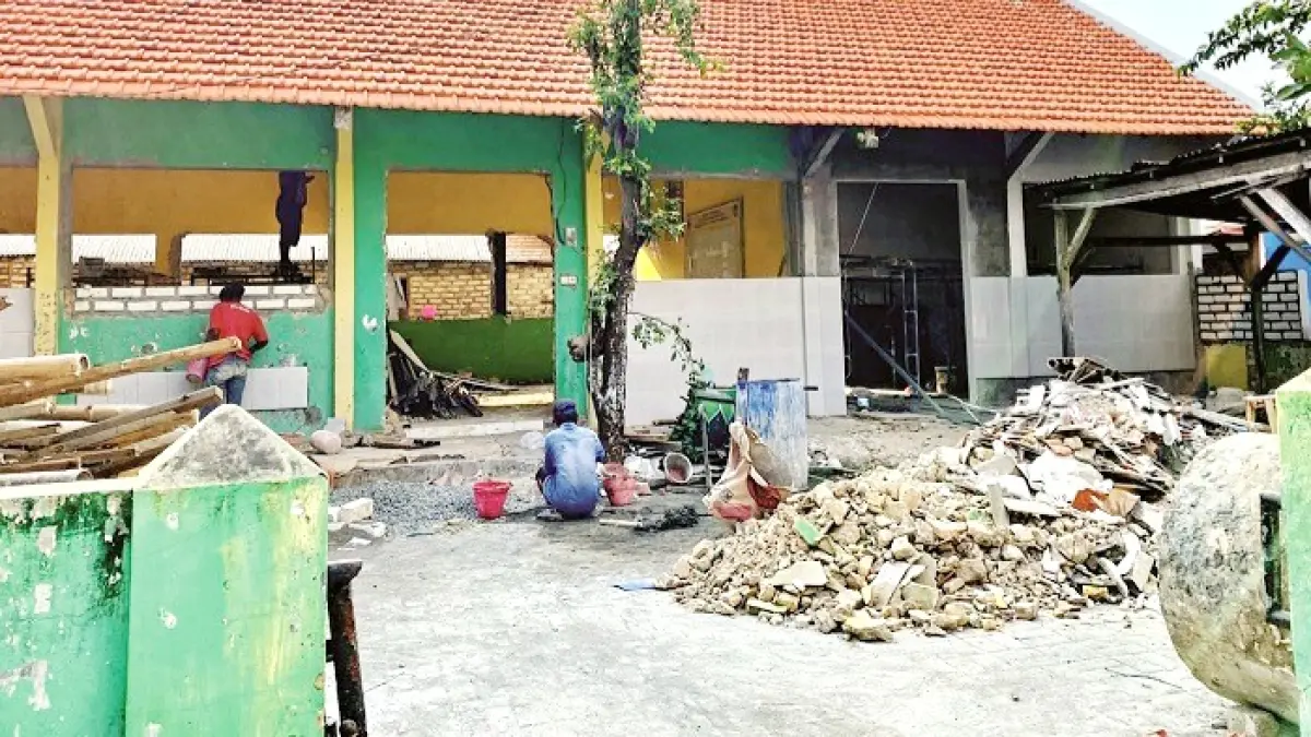 DIBONGKAR: Warga berkendara di depan SDN Martajasah yang tengah direhabilitasi, Senin (7/9). (VIVIN AGUSTIN HARTONO/JPRM)
