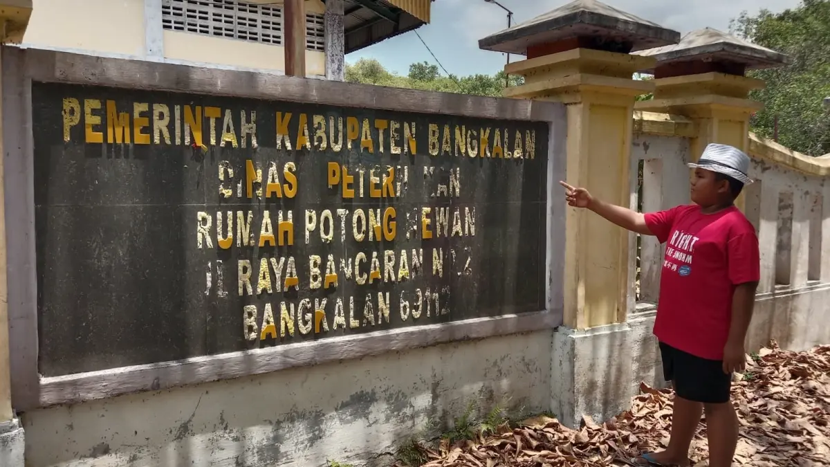 TAK TERAWAT: Seorang bocah berdiri di dekat gedung RPH Dinas Peternakan Bangkalan yang catnya mulai mengelupas, Minggu (20/9).