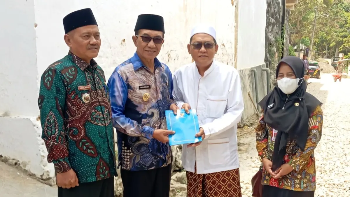 KOMITMEN: Bupati Pamekasan KH. Kholilurrahman menyerahkan bantuan uang tunai kepada warga Desa Pegantenan, Kecamatan Pegantenan, yang melakukan swadaya perbaikan jalan, Kamis (24/9). (M. KHOLIL RAMLI/JPRM)