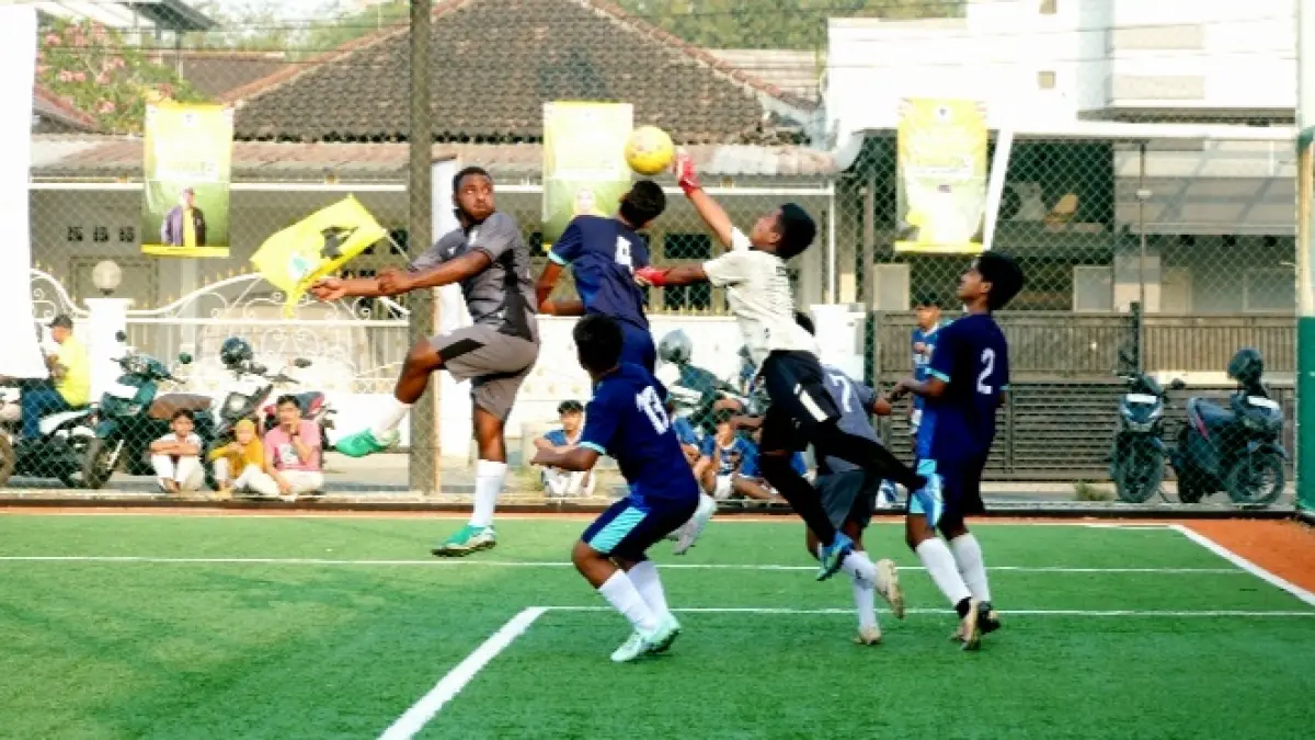 BEREBUT DI UDARA: Pemain SMAN Rambipuji Yunus Fefanya Babingga (kiri), berebut bola atas dengan kiper SMKN 2 Jember dalam pertandingan semifinal Bahlil Mini Soccer Zona 10 Jember pada Jumat (2/10) sore. Pertandingan itu dimenangkan SMAN Rambipuji dengan skor 2-1. (SIDKIN ALI/RADAR JEMBER)