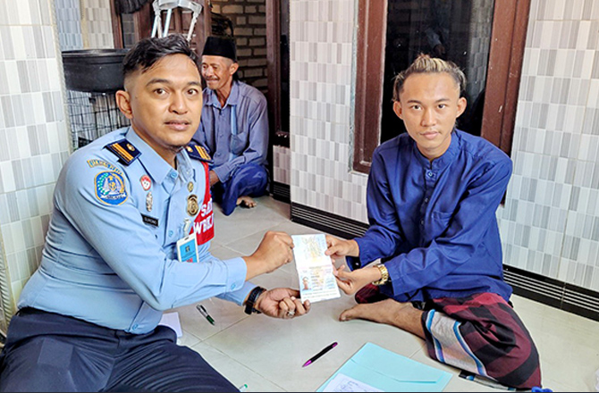 SENANG: Robi Ansalni menerima paspor dari Kepala Subseksi Pelayanan dan Verifikasi Dokumen Keimigrasian Agus Surono. (IMIGRASI UNTUK RadarMadura.id)