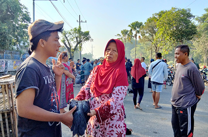 DIMINATI: Beberapa warga melakukan transaksi jual beli ayam di Jalan Ahmad Yani Bangkalan kemarin. (AYU LATIFAH/RadarMadura.id)