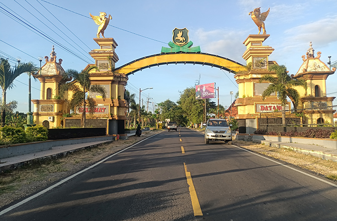 BELUM DIKERJAKAN: Pengguna jalan melintas di tugu selamat datang yang berlokasi di Kecamatan Pragaan, Sumenep, kemarin. (MOH. IQBAL/RadarMadura.id)