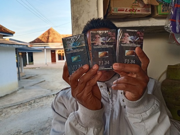BEBER: Warga menunjukkan kemasan rokok tanpa pita cukai yang beredar di Kecamatan Sokobanah, Sampang, kemarin. (ZEINAL ABIDIN/RadarMadura.id)