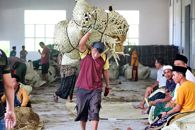 PENUH HARAP: Pekerja memanggul tembakau untuk ditimbang di Gudang Bawang Mas, Desa Blumbungan, Kecamatan Larangan, Pamekasan, kemarin. (MOH. IQBAL AFGANI/RadarMadura.id)