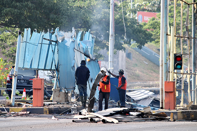 DIRATAKAN: Pekerja membongkar bangunan pintu tol Jembatan Suramadu sisi Madura kemarin. (VIVIN AGUSTIN HARTONO/RadarMadura.id)