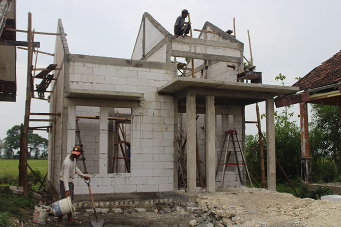 BELUM TUNTAS: Pekerja melanjutkan pembangunan rumdin guru SMPN 2 Socah, Bangkalan, kemarin. (VIVIN AGUSTIN HARTONO/Radarmadura.id)