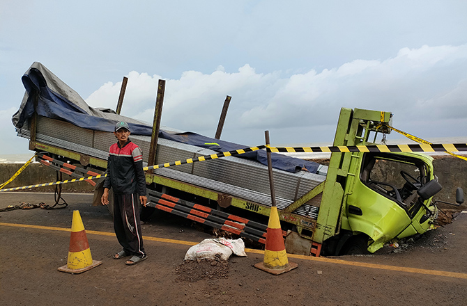 BAHAYA: Warga mengatur lalu lintas di lokasi kecelakaan tunggal truk terperosok lubang di Jalan Raya Tamberu, Kecamatan Batumarmar, Pamekasan, kemarin. (MOH. IQBAL AFGANI/Radarmadura.id)