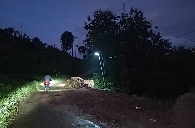 BELUM TUNTAS: Warga melintas di dekat tumpukan material yang digunakan untuk memperbaiki jalan longsor di Desa Tamberu Laok, Kecamatan Sokobanah, Sampang, kemarin. (ZEINAL ABIDIN/Radarmadura.id)