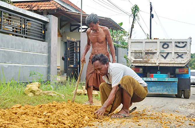 GOTONG ROYONG: Warga menambal jalan rusak di Desa Campor, Kecamatan Geger, Bangkalan, kemarin. (ABRAR GHAZY HARDIAN/Radarmadura.id)