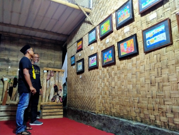 MENINJAU: Chairul Alwan dan Kabiro JPRM Sampang Hendriyanto melihat karya seni lukis di Sanggar Mbah Kung, Jalan Salak 77, Sampang, Sabtu (25/2). (FADIL/JPRM)