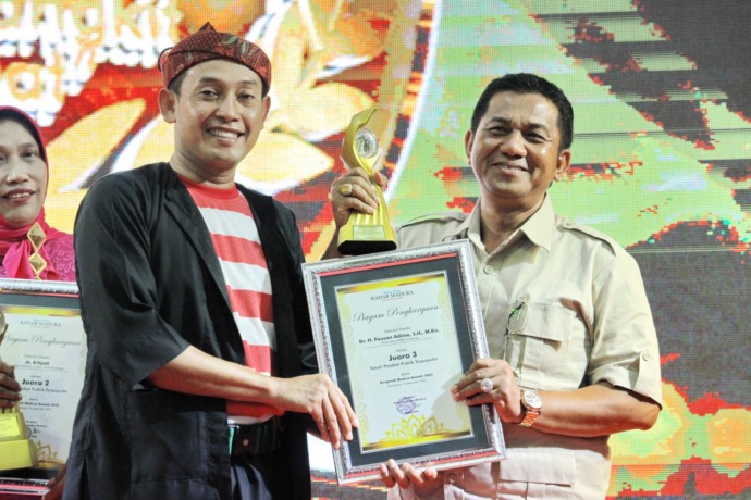 TELADAN: Wakil Bupati Sampang Abdullah Hidayat menyerahkan trofi dan piagam Tokoh Pejabat Publik Terpopuler III Madura Awards 2022 kepada Wakil Ketua DPRD Sampang Fauzan Adima di Gedung Bakorwil Pamekasan, Jumat, 16 Desember 2022. (VIVIN AGUSTIN HARTONO/J